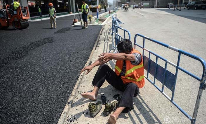 ชีวิตต้องสู้! ภาพคนงานสร้างถนนในจีน ร้อนจัดจนเท้าพอง