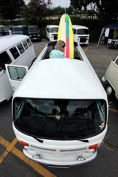 A man arranges his surfboard inside his Volkswagen