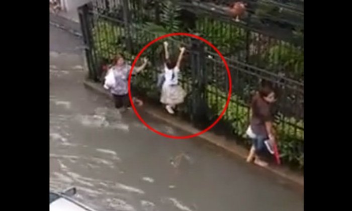 ภาพเด็กปีนรั้วหลบคลื่นน้ำท่วม หลังฝนตกหนักวานนี้