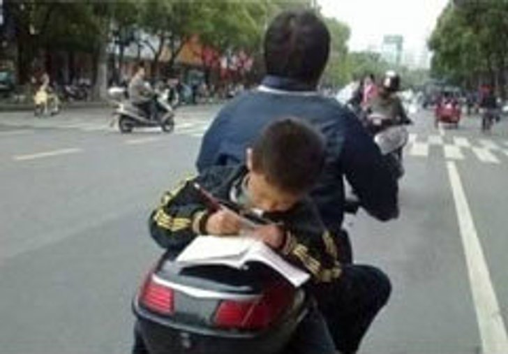 พ่อแม่รังแกฉัน! ภาพเด็กจีนทำการบ้าน บนรถมอเตอร์ไซด์