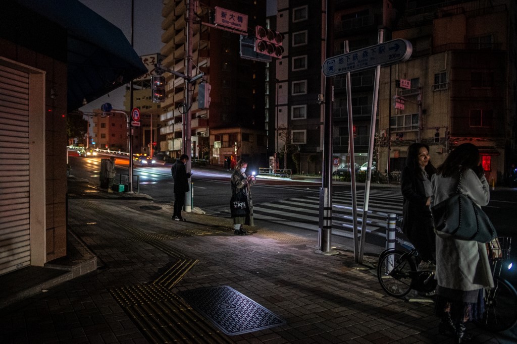 ชาวบ้านในเขตโคโต กรุงโตเกียว ออกมาสังเกตการณ์ริมถนน ระหว่างไฟฟ้าดับ เมื่อช่วงก่อนเช้ามืดของวันที่ 17 มี.ค. 2565