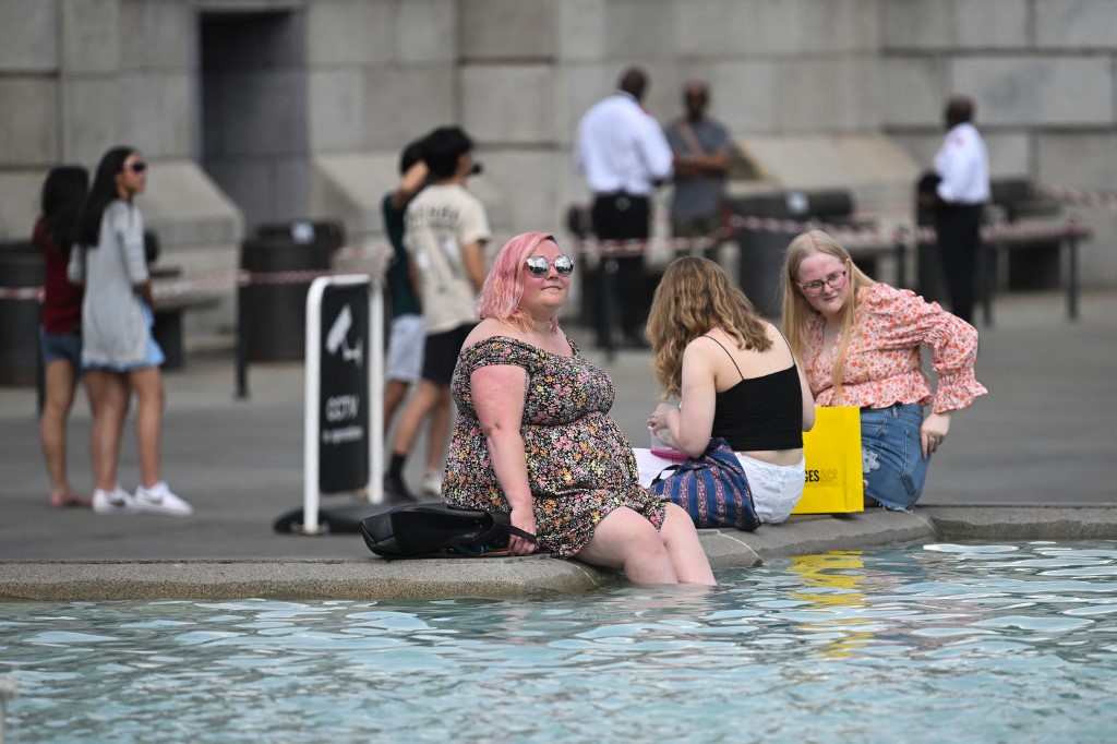 คนเดินถนนนำเท้าลงจุ่มน้ำเพื่อคลายความร้อนที่จัตุรัสทระแฟลเกอร์ ในกรุงลอนดอน สหราชอาณาจักร เมื่อวันที่ 13 ก.ค.  2565