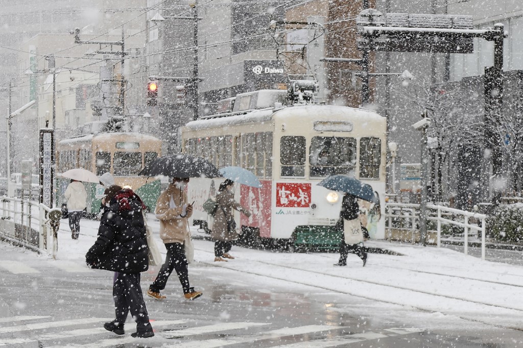 ผู้คนในเมืองโทะยะมะ จ.โทะยะมะ เดินกางร่มเพื่อป้องกันหิมะที่ตกลงมาอย่างหนัก เมื่อวันที่ 24 ม.ค. 2566