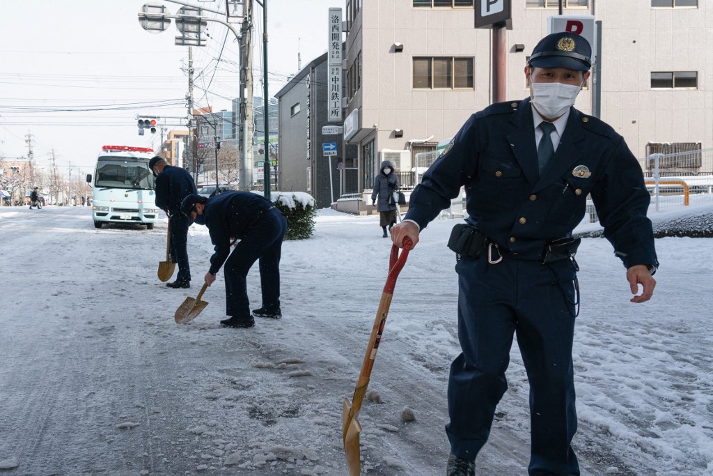 ตำรวจในเมืองเกียวโต ของญี่ปุ่น พยายามทุบน้ำแข็งที่จับตัวบนพื้นถนนให้แตกและตักออก เมื่อวันที่ 25 ม.ค. 2566