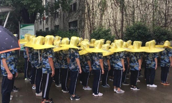 สดใสวันฝนพรำ นักเรียนจีนใส่ร่มกันฝนจานบินฝึกทหาร