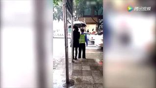 ชาวเน็ตประทับใจ! หญิงชาวจีนยืนกางร่มให้ตำรวจทำงานกลางสายฝน