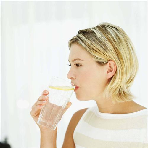 Side profile of a young woman drinking water from a glass