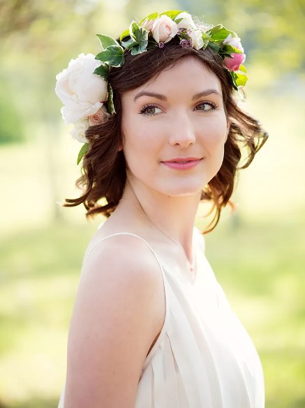 Short curly wedding hairstyle with an ivy and rose flower crown