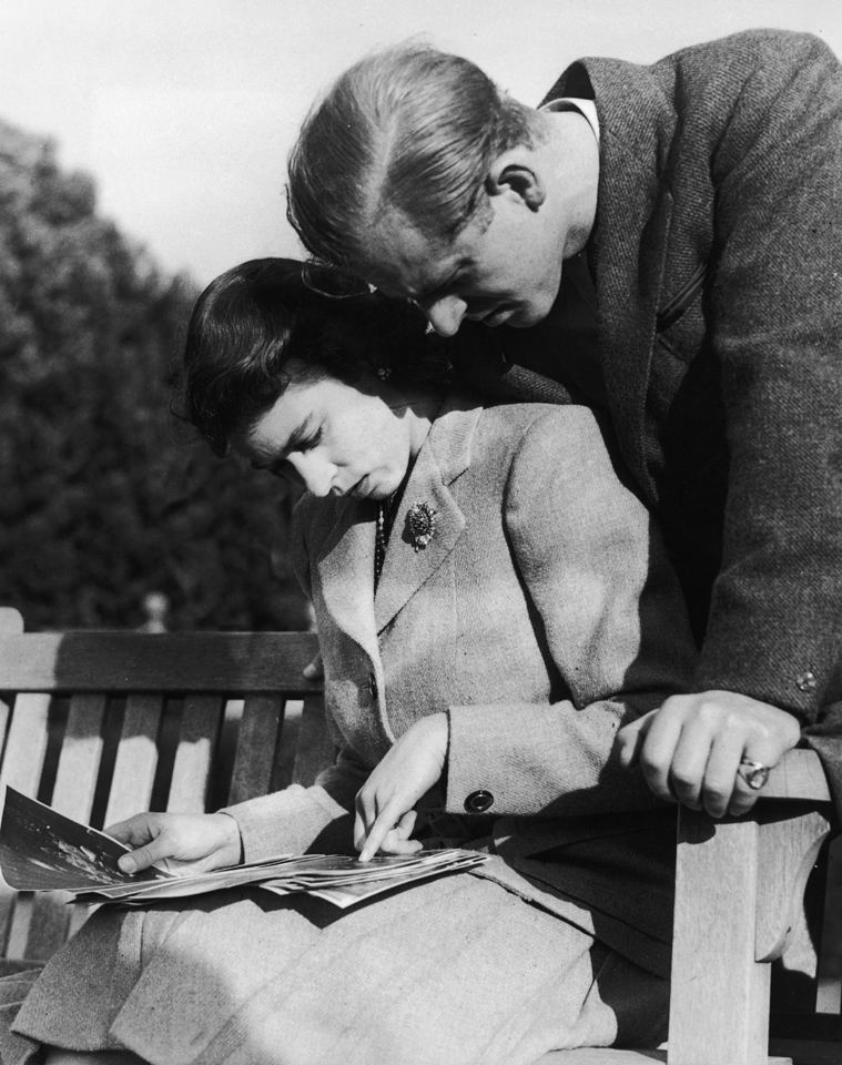 Queen Elizabeth II and her husband, Philip Mountbatten, study their wedding photographs while on honeymoon in Romsey, Hampshire, November 1947